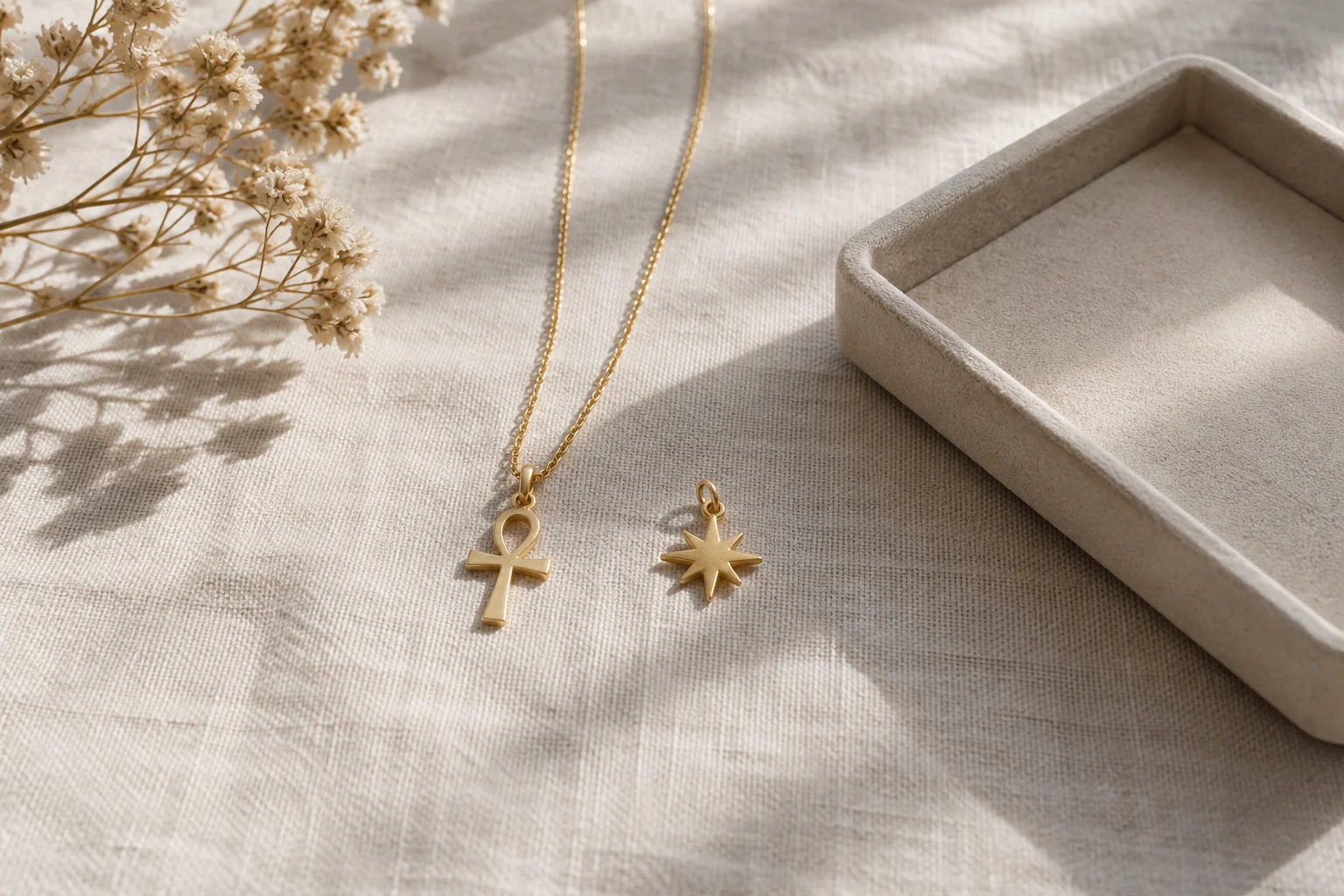 Un pendentif ankh et une petite étoile présentés séparément sur du lin.